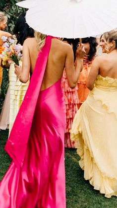 a woman in a pink dress is holding an umbrella and some other women are standing around