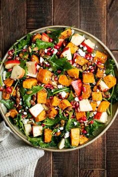 a salad with spinach, apples and cheese in a bowl on top of a wooden table