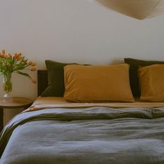 a bed with several pillows and two vases on the end table next to it