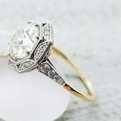 a diamond ring sitting on top of a white piece of glass with diamonds around it