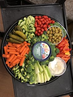 a platter filled with vegetables and dips on top of a black tablecloth