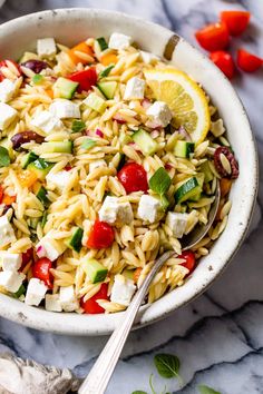 a white bowl filled with pasta salad and topped with feta cheese