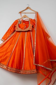 The Persimmon Mirror Lehenga Set features a stunning persimmon orange lehenga adorned with intricate mirror work, paired with a stylish blouse and a matching dupatta. Perfect for festive celebrations, this dazzling ensemble blends traditional charm with modern elegance, making it ideal for weddings, festivals, and special occasions. Orange Cutdana Sharara With Traditional Drape, Orange Sharara With Cutdana For Diwali, Festive Anarkali Style Orange Sharara, Festive Anarkali Orange Sharara, Orange Cutdana Sharara For Diwali, Festive Orange Anarkali Sharara, Orange Traditional Drape Set With Cutdana, Festive Orange Sharara With Dupatta, Orange Sharara With Traditional Drape For Festive Occasions