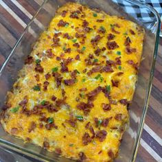 a cheesy casserole in a glass dish on top of a wooden table