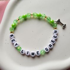 "Key Lime Green" bracelet, on a stretch chord - referencing The Last Great American Dynasty.  If there are any designs you are looking for but can't find, send me a message and I can create it for you.  **Due to the nature of the material of the beads, I recommend keeping your bracelets dry and away from water or chemicals when possible. The white and light color beads will show wear and tear/dirt quicker than the darker colors. Keeping the bracelets dry and away from lotions, chemicals, dyed garments, etc. will help keep them looking new for much longer.                                                                                                                  -Alyssa from LyssieBCreations The Last Great American Dynasty Bracelet, Novelty Green Beaded Bracelets, Green Novelty Bracelets With Round Beads, Novelty Green Beaded Bracelets For Friendship, Handmade Inspirational Stretch Bracelet, Green Novelty Jewelry With Letter Beads, Customizable Green Bracelet Jewelry, Green Stretch Bangle Bracelet For Friendship, Customizable Adjustable Spiritual Stretch Bracelet