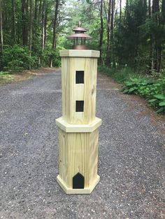 two tall wooden towers sitting on top of a gravel road in the middle of a forest