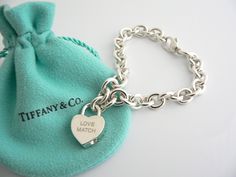 Offered for sale is a wonderful and rare Tiffany and Co. Sterling Silver "Love Match" Heart Padlock bracelet. The piece is made from substantial and bright Tiffany silver, and yet retains a very feminine feel to it. Attached to its very substantial Tiffany Silver charm bracelet is a Heart padlock charm with "Love Match" engraved on it. The"Love Match" padlock charm opens and closes and thus can be used as a charm on a necklace or as part of another charm bracelet! Super versatile piece! It is a Luxury Sterling Silver Heart Bracelet For Gift, Luxury Sterling Silver Bracelets For Valentine's Day, Luxury Sterling Silver Heart Bracelet For Anniversary, Luxury Silver Bracelets For Valentine's Day, Luxury White Gold Heart Bracelet, Luxury White Gold Bracelet With Heart Charm, Luxury Wedding Heart Bracelet With Heart Charm, Luxury Sterling Silver Heart Bracelet For Valentine's Day, Luxury Heart Charm Bracelet Gift