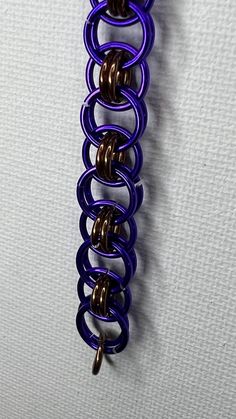 a purple metal object hanging from the side of a white wall with brown and blue springs attached to it