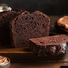 two slices of chocolate cake sitting on top of a wooden cutting board