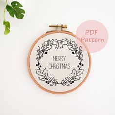 a cross stitch christmas wreath with the words merry christmas in black and white on it