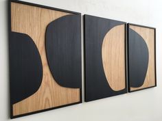 three black and wood paintings hanging on the wall