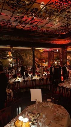 a dining room filled with lots of tables covered in white tablecloths and place settings