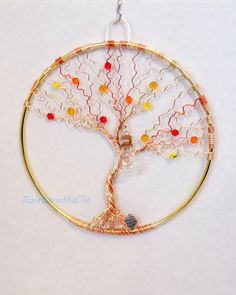 a tree of life pendant is shown on a white background with orange, yellow and red beads