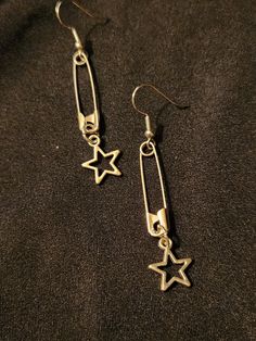 Safety pins on earring hooks, accented with open (hollow) star charms, set of 2 earrings, each measures about 2.5 inches.  Silver tone.  Handmade, unisex jewelry.  Ready to ship. To continue shopping: http://www.rrrobinnn.etsy.com Heart Safety Pin Earrings Target, Cool Earrings Hot Topic, Cheap Silver Hoop Beaded Earrings, Affordable Handmade Star Earrings, Cheap Trendy Dangle Charms, Cheap Adjustable Jewelry For School, Luxury Modern Metal Plug Earrings, Cheap Edgy Jewelry, Affordable Grunge Festival Jewelry