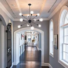 a long hallway with arched windows and white trim on the walls, along with dark wood flooring