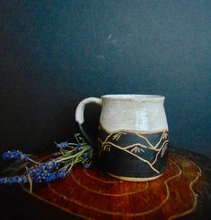 a black and white mug sitting on top of a wooden table next to a blue wall