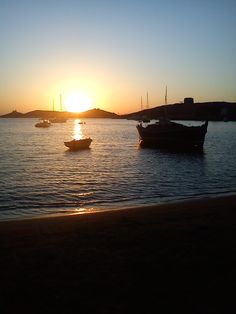 the sun is setting over some boats in the water