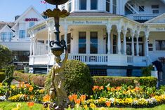 a statue in front of a hotel with flowers around it