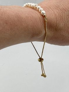 A delicate bracelet made from brass with a line of fresh water pears across the top of the wrist. The bracelet can be adjusted for fit. Easily worn alone or layered with your other favorite bracelets. We love ours for its versatility. Details: Adjustable chainlink bracelet Size: Inside length (when adjusted for maximum size: ~ 4.5" (11.5 cm), strip with pearls: 2.25" (6 cm), diameter of pearls average ~ 0.2" (0.5 cm) Material: brass and freshwater pearls CARE - Avoid contact with body products. Simple Chain, String Of Pearls, Fresh Water Pearls, Water Pearls, Body Products, Bracelet Sizes, Delicate Bracelet, Bracelet Making, Chain Link