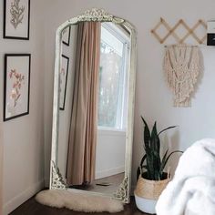 a large mirror sitting on top of a wooden floor next to a potted plant