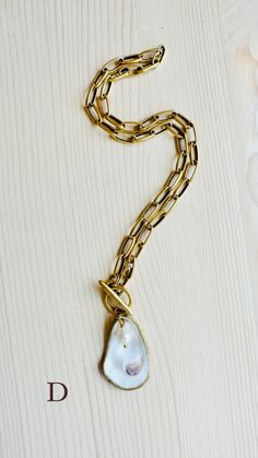 A truly One-of-a-Kind statement piece. Hand painted gold leaf natural oyster shell pendants with gorgeous freshwater pearls, on high quality 12K Gold over brass chain with toggle front closures. Each shell has been harvested in our Charleston, SC rivers and are carefully hand finished to create its one-of-a-kind appearance. No two shells are alike. Each oyster shell has its own story behind its journey to the shore. The size, shape and colors in each one will vary and that is what makes each she Journey To The Shore, Oyster Shell, Detail Shop, Shell Pendant, Shell Necklaces, Charleston Sc, Brass Chain, Gold Leaf, Charleston