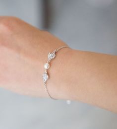 a woman's arm wearing a bracelet with flowers and pearls on the clasps