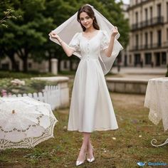 a woman in a white dress and veil posing for the camera with her hands on her hips