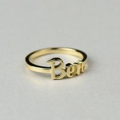 Perfect for new mothers and babies, this solid gold name text script ring is completely personalized with whatever text you want. Available in 14k, 18k yellow, rose, white gold & platinum--just choose your desired metal from the drop-down menu before checkout. HOW TO ORDER: Please specify the text in the order notes during checkout. Details: * Default size is approx. 7mm tall for the text, and the band is 1.8mm x 1mm. Contact us if you want different dimensions. * We can do the finish as mat Personalized 14k Gold Promise Ring, Customizable Yellow Gold Promise Ring, Elegant Custom Name Engraved Ring For Mother's Day, Personalized Yellow Gold Ring, Personalized Initial Ring In Yellow Gold, Customizable Gold Initial Ring, Gold Personalized Promise Ring, Personalized Yellow Gold Initial Ring For Promise, Customizable Yellow Gold Ring For Personalized Gift