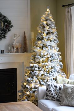 a decorated christmas tree in front of a fireplace with white and silver ornaments on it