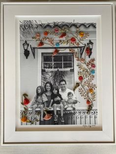 the family is sitting together in front of a window with flowers and leaves on it