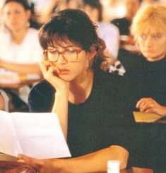 two women sitting at a table with papers in front of them and one woman holding a pen