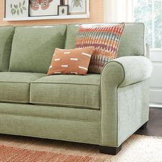 a green couch with pillows on it in a living room