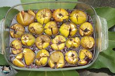 a dish filled with lots of fruit sitting on top of a leaf covered ground next to leaves