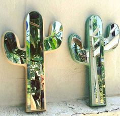 three mirrors mounted to the side of a wall next to a cactus shaped mirror on top of a shelf