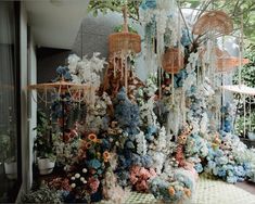 an arrangement of flowers and birdcages hanging from the ceiling