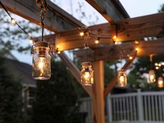 mason jar lights hanging from a wooden pergolan with string lights on the outside