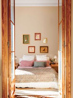 a bed sitting in the middle of a bedroom with pictures on the wall above it