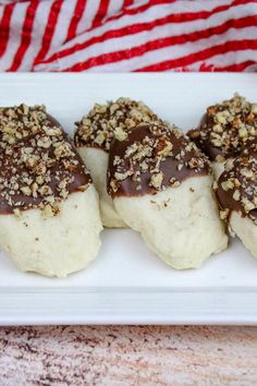 four pieces of chocolate covered dough on a white plate with a red and white striped towel