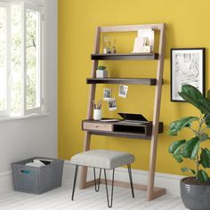 a room with yellow walls and a wooden ladder desk in the corner next to a potted plant