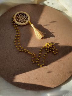 a tasseled necklace with beads and a wooden bead in the shape of a dream catcher