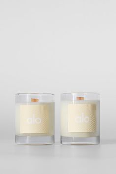 two candles sitting next to each other on a white counter top, one candle has the word alo written in it