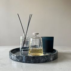 two glass bottles with reeds on a marble tray