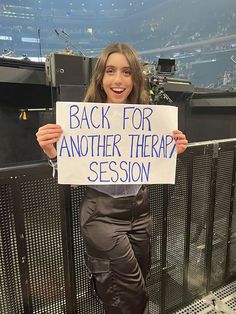 a woman holding up a sign that says back for another therap? session