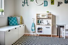 a child's playroom with white furniture and green accents on the wall, along with black and white chevron rug