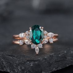 a ring with an emerald and white diamond in the center on top of a rock