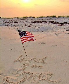 an american flag is in the sand with some writing on it