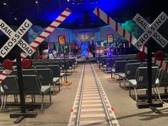 a train track with railroad crossing signs on it's sides in front of a stage