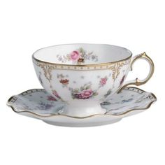 a tea cup and saucer with gold trimmings on the rim, decorated with pink flowers