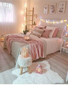 a bedroom decorated in pink and white with lights on the wall, bedding and rugs