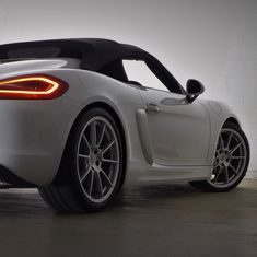 the back end of a white sports car parked in a garage with its lights on